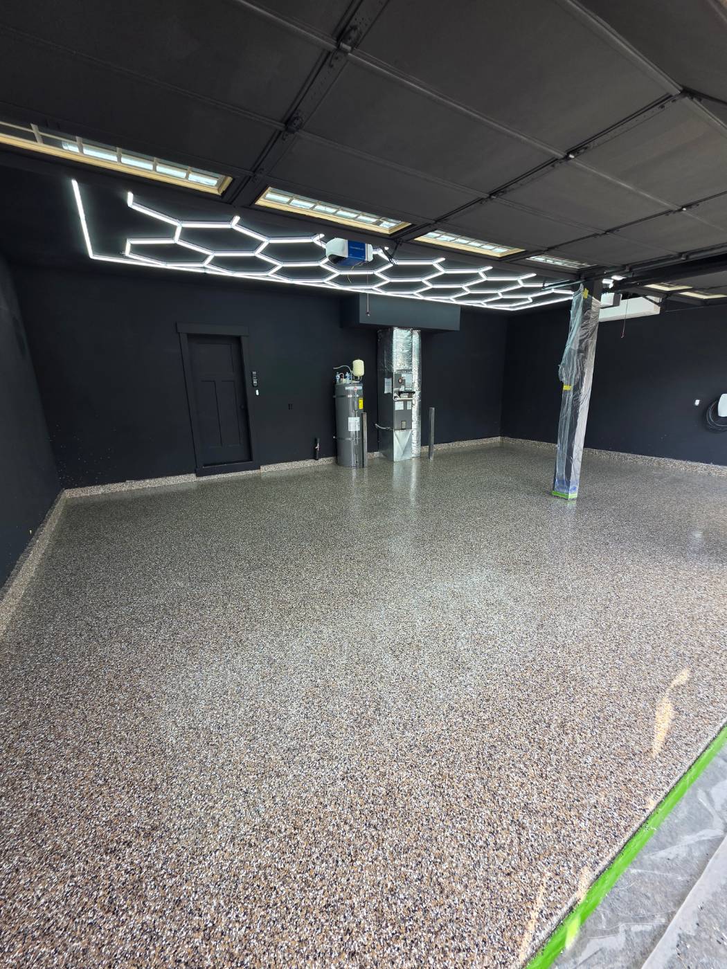 Finished flake floor in a black-walled garage under hexagon lighting