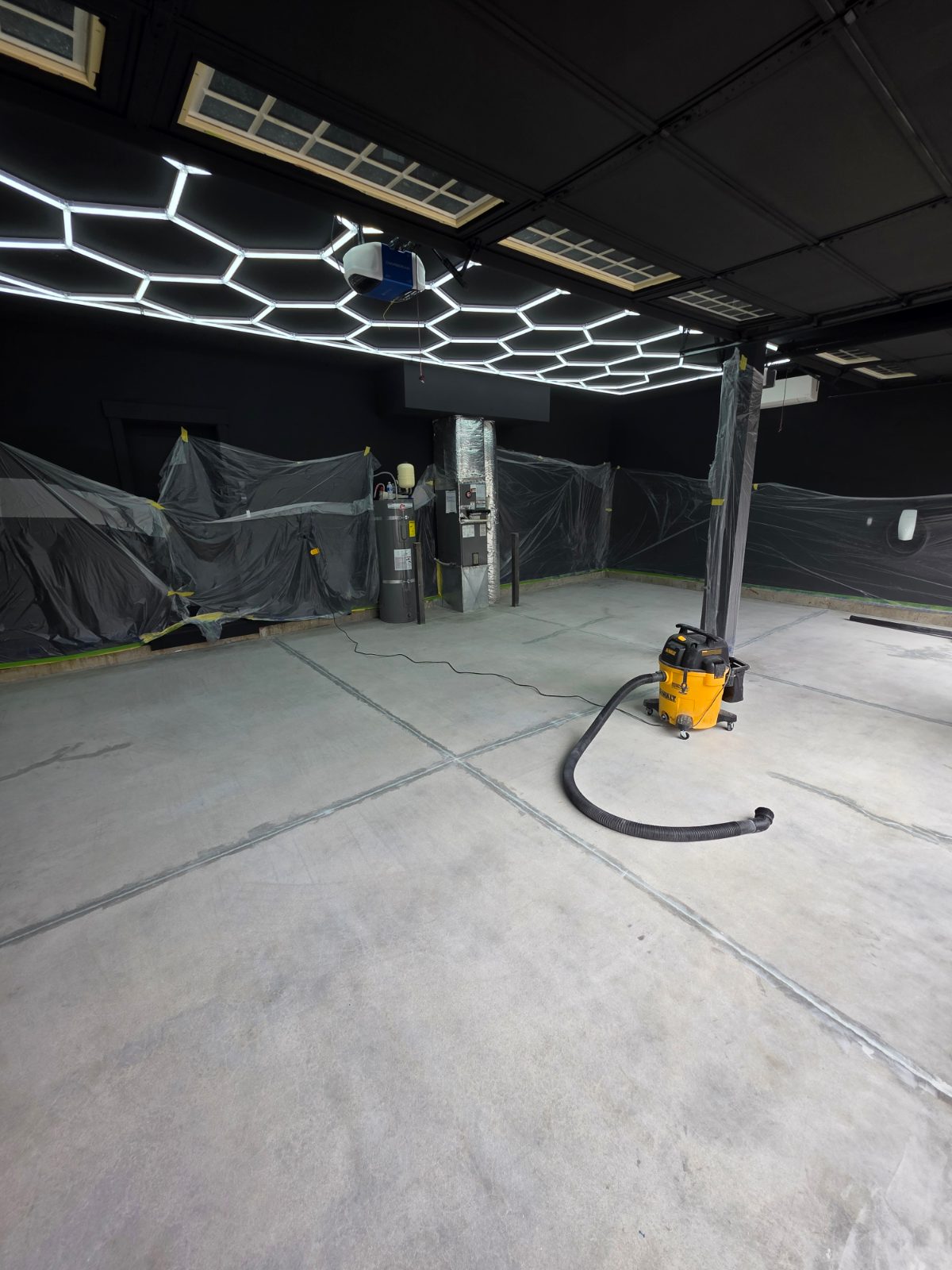 Bare grey concrete garage floor, taped off and vacuumed, ready to grind